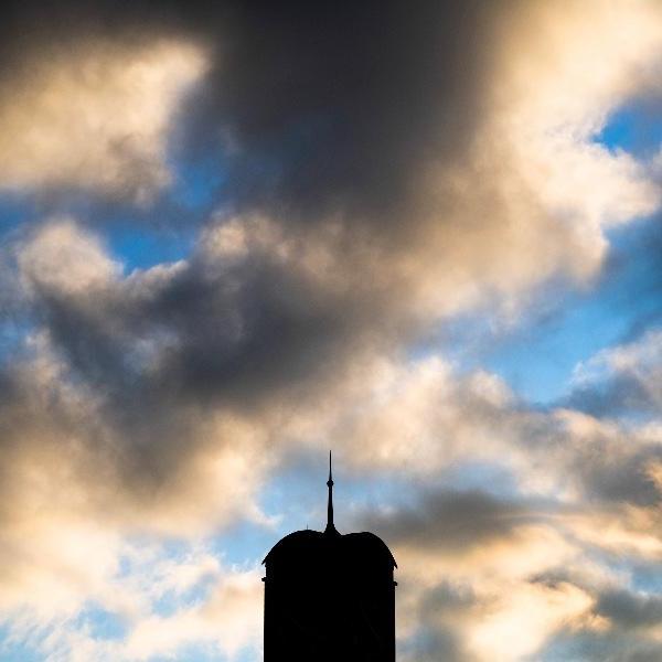 钟楼的剪影映衬着白云飘飘的蓝天.